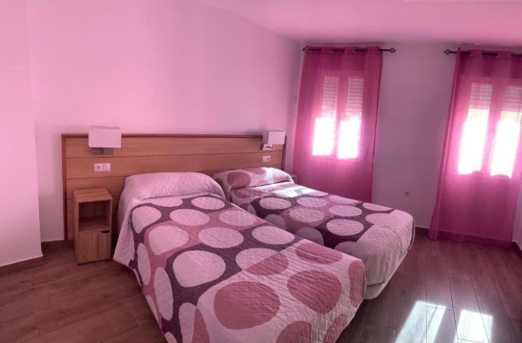 Bright twin room with curtains and wooden floor